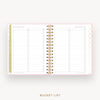 An open spiral-bound planner or notebook showing a 'Bucket List' page layout with lined sections, checkboxes, and decorative gold polka dots on a white page, set against a light gray background with the words 'BUCKET LIST' below.