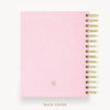 A light pink textured spiral notebook shown from the back, featuring a gold-tone spiral binding along the right edge and a small circular monogram logo near the bottom. The text 'BACK COVER' is printed below the notebook on a clean white background.