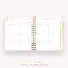 An open spiral-bound weekly planner page with white pages, gold rings, and delicate gold and pink decorative accents, shown on a light gray background with the text 'WEEKLY PLANNING PAGE' below.