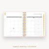 An open tabbed monthly calendar planner shown from the front, with January 2027 visible on the right page and a gold spiral binding down the center. The pages are white with light gray grid headers and subtle gold confetti accents on the left margin.