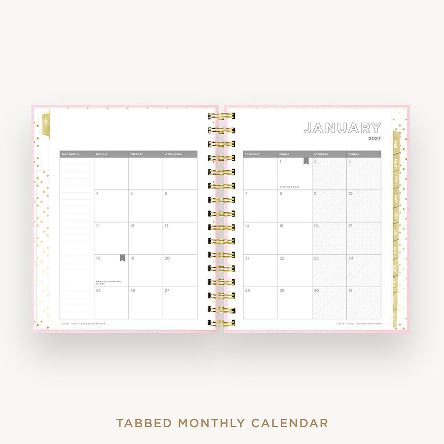 An open tabbed monthly calendar planner shown from the front, with January 2027 visible on the right page and a gold spiral binding down the center. The pages are white with light gray grid headers and subtle gold confetti accents on the left margin.