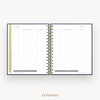 An open spiral-bound planner or notebook showing an expenses page with lined columns, gold ring binding, and a gold vertical tab on the left margin, centered on a light gray background with the word EXPENSES below.