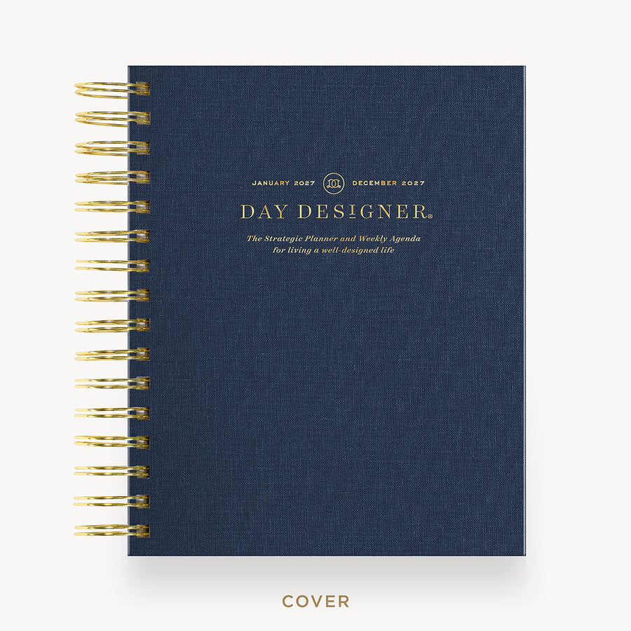 A navy blue spiral-bound planner cover with gold wire binding and gold text reading 'DAY DESIGNER' on a clean white background.