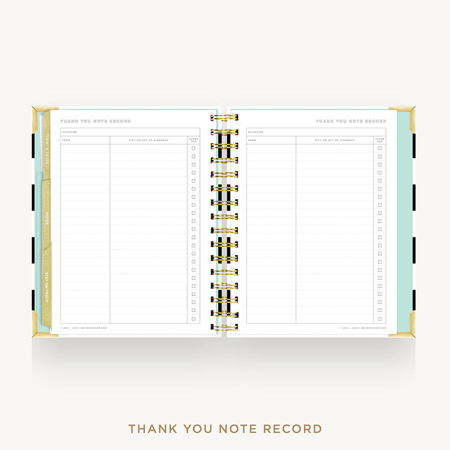 An open spiral-bound thank you note record planner on a light gray background. The pages are white with gold lines and columns, and the cover edges show pastel green, gold, and black accents.