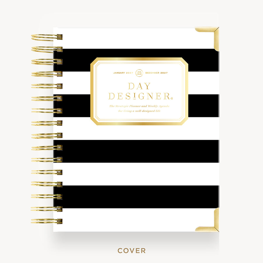 A spiral-bound planner or notebook cover with bold horizontal black and white stripes and a gold decorative label reading 'DAY DESIGNER.' The cover is shown front-on against a light neutral background, with gold spiral binding visible along the left side.