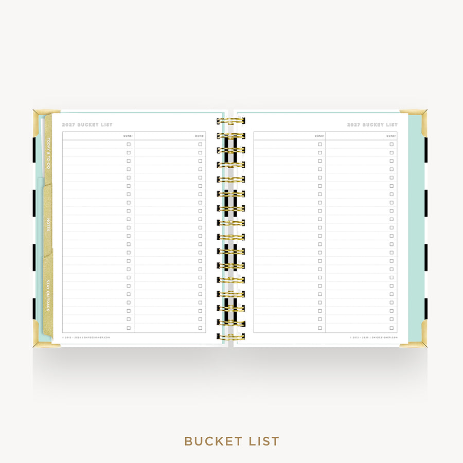 An open spiral-bound planner or notebook showing a bucket list page layout with lined sections and checkboxes, gold rings, and pastel side accents on a light gray background.