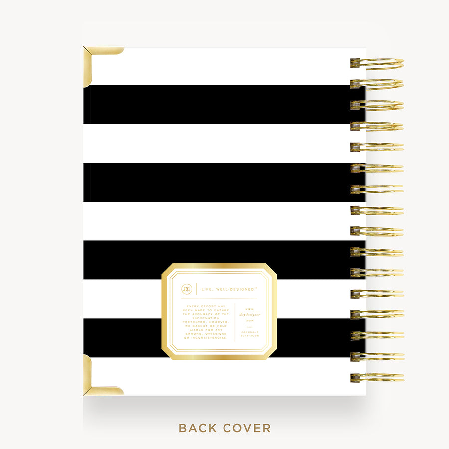 A spiral-bound planner or notebook shown from the back cover, featuring bold horizontal black and white stripes with gold corner accents and a gold-bordered label area. The right side shows a gold spiral binding.