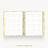 An open 12-month overview planner with a gold spiral binding and a yellow floral patterned cover, displayed on a light gray background with the text '12-MONTH OVERVIEW' below.