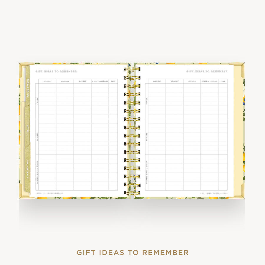 An open spiral-bound planner or notebook with floral gold and green patterned pages, showing two columns of gift ideas to remember tables. The text 'GIFT IDEAS TO REMEMBER' appears below on a light gray background.