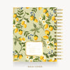 A spiral-bound planner or notebook shown from the front and back cover. The cover has a light sage green background with a repeating pattern of yellow lemons, green leaves, white flowers, and small blue berries.
