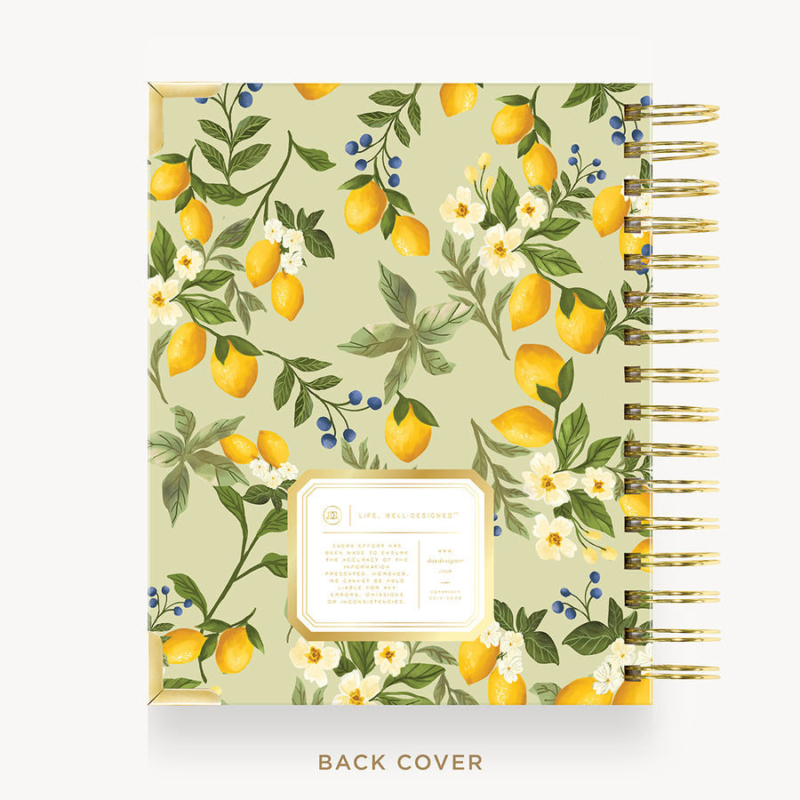 A spiral-bound planner or notebook shown from the front and back cover. The cover has a light sage green background with a repeating pattern of yellow lemons, green leaves, white flowers, and small blue berries.