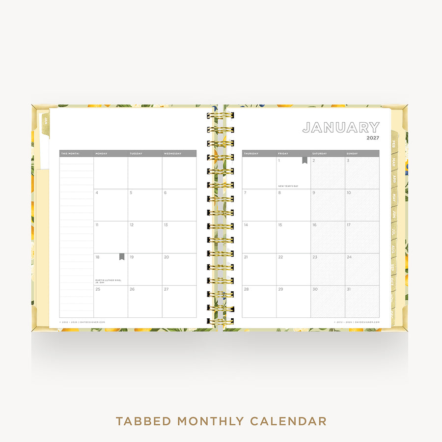 An open spiral-bound monthly calendar planner on a light gray background. The pages are white with a floral-patterned gold and green cover, and the left page shows tabs.