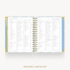 An open spiral-bound planner or notebook showing a packing checklist page spread across both sides, with a gold spiral binding and a light blue patterned cover, on a light gray background with the text 'PACKING CHECKLIST' below.