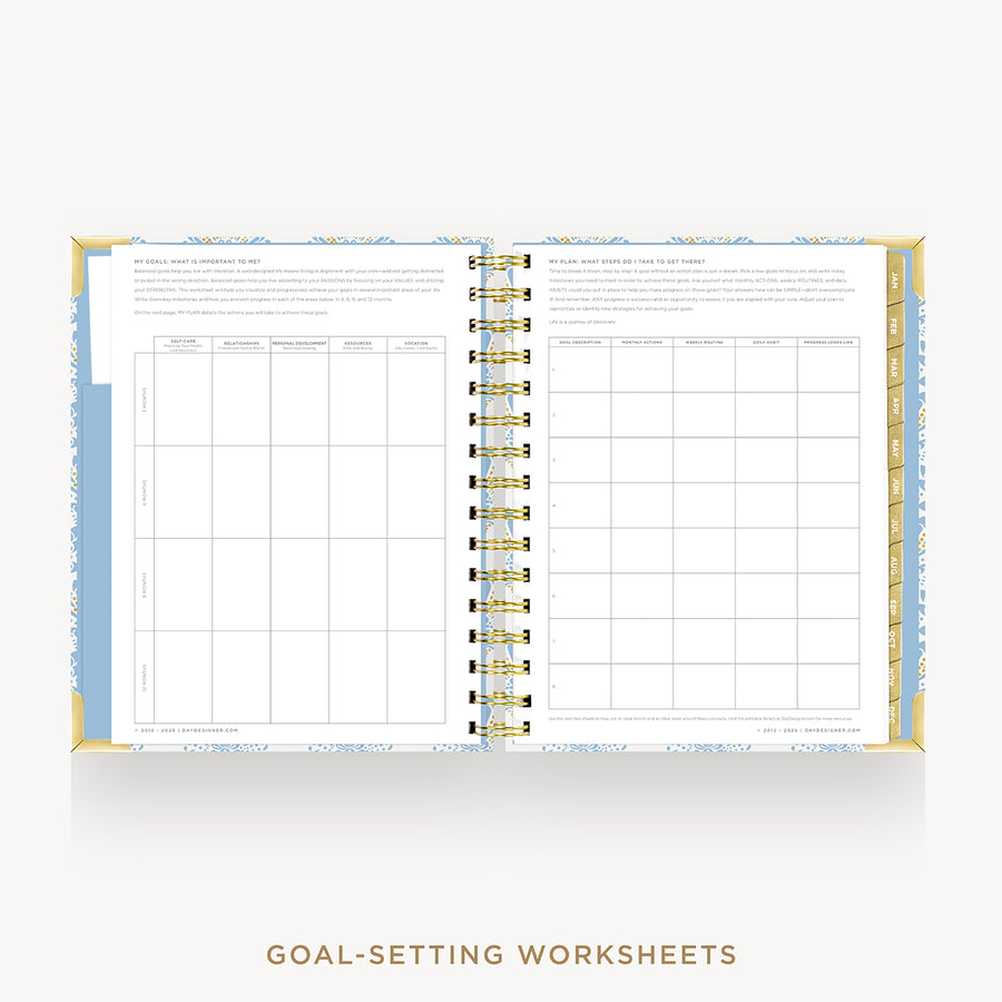 An open spiral-bound planner or workbook showing two pages of goal-setting worksheets, with a gold wire binding and a light blue and white patterned cover, on a light gray background. Text below reads 'GOAL-SETTING WORKSHEETS'.
