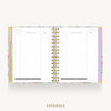 An open spiral-bound planner or notebook showing a floral-patterned expense page spread, photographed on a light gray background with the word EXPENSES below.