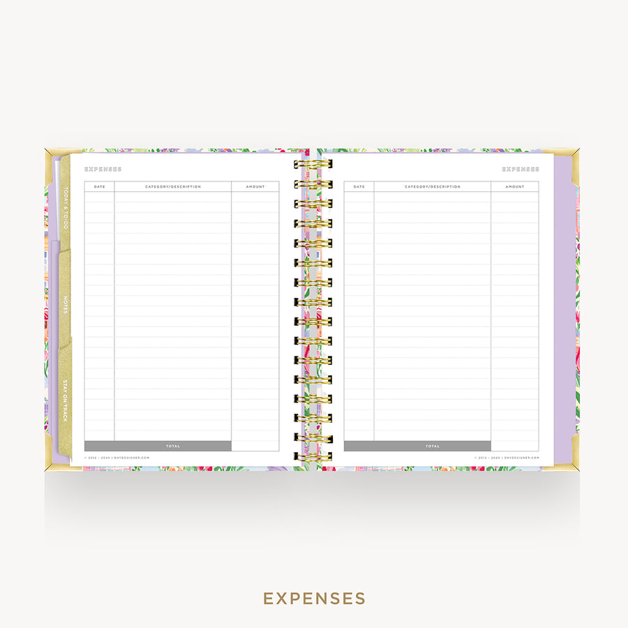 An open spiral-bound planner or notebook showing a floral-patterned expense page spread, photographed on a light gray background with the word EXPENSES below.