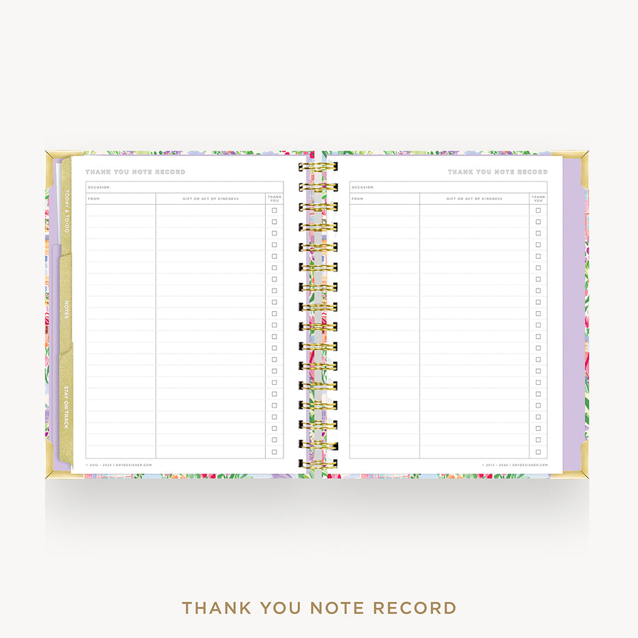 An open spiral-bound thank you note record planner shown from above on a light gray background. The pages are white with lined sections and checkboxes, and the cover and inner border feature a pastel floral pattern with gold-toned rings and trim.