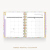 An open tabbed monthly calendar planner shown from above on a light gray background. The cover has a pastel floral pattern with lavender, pink, green, and gold accents.