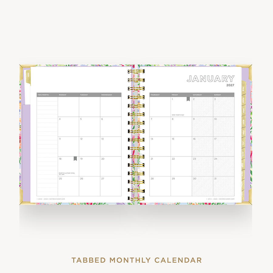An open tabbed monthly calendar planner shown from above on a light gray background. The cover has a pastel floral pattern with lavender, pink, green, and gold accents.