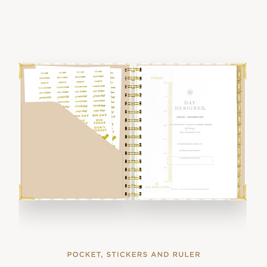 An open spiral planner or pocket organizer with gold-toned rings, cream and beige pages, and gold text, shown on a light gray background. The bottom text reads 'POCKET, STICKERS AND RULER'.