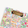 Clipboard with a colorful floral and village design on a white background