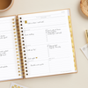 weekly planner, open book, written on pages, gold stickers, tea cup, gold pen, stationery, wood dish