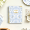 mini notebook with blue and gold block print pattern, beige background, plate, cloth, flowers, paper clip, basket, antique cup