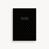 Black notebook with white polka dots and 'NOTES' label on a light gray background