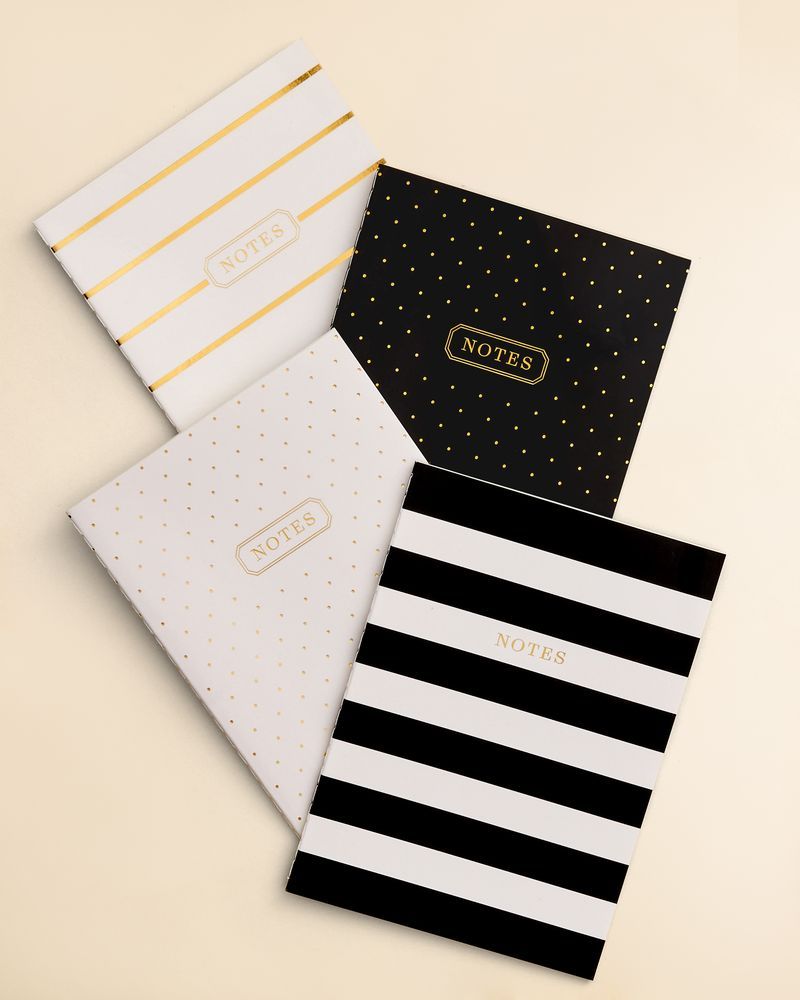 Four notebooks with different cover designs on a beige background