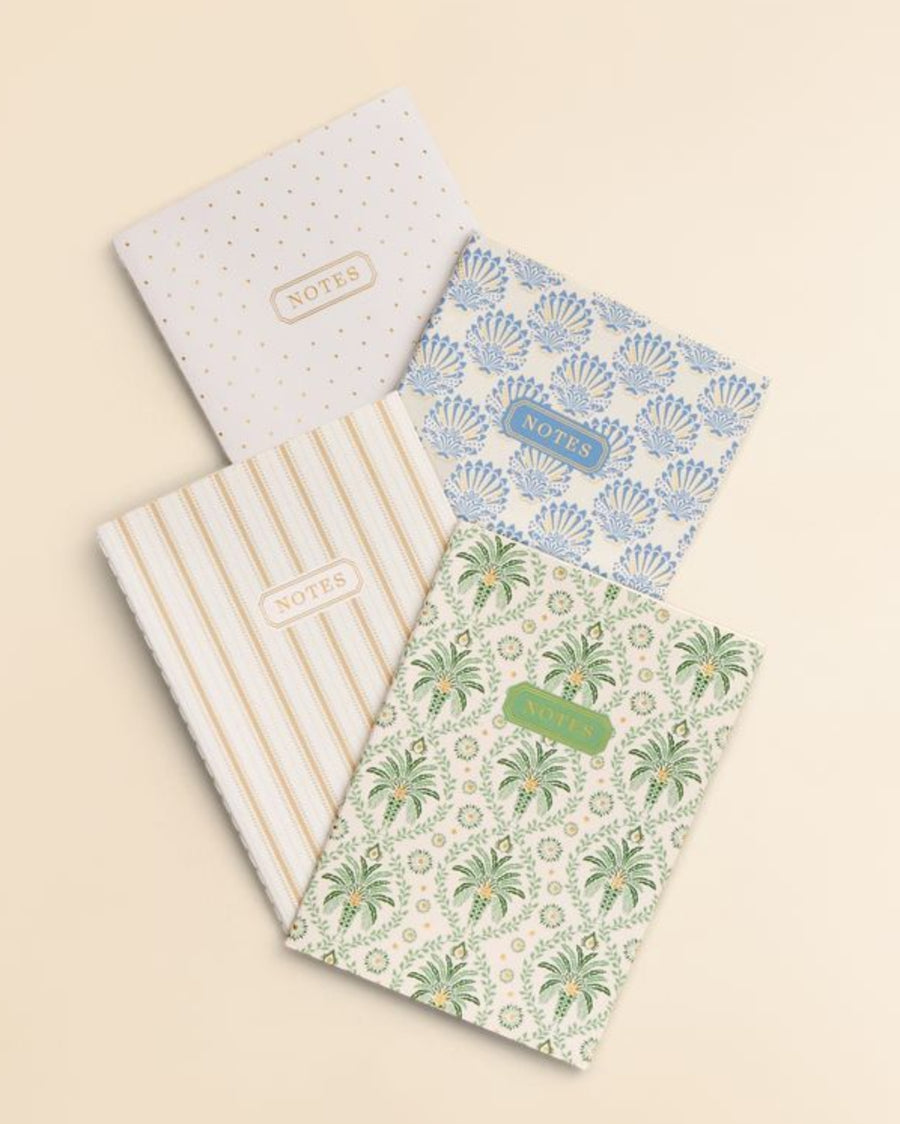 Set of four notebooks with different designs on a beige background
