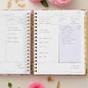 open book planner, written on pages, lined sticky note, beige background, pink flowers, gold accessories