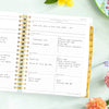 weekly planner, open book, written on pages, light mint background, multi-colored flowers, dish