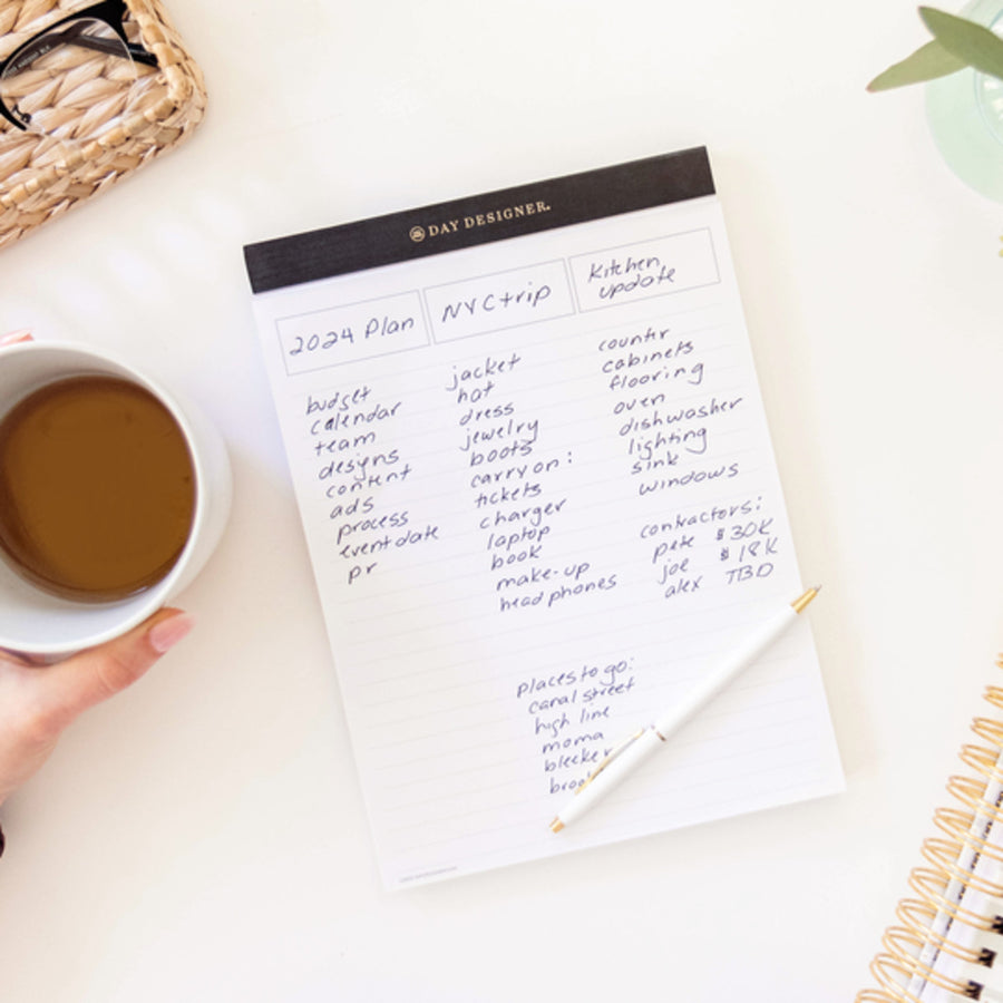 written on notepad with black trim, coffee cup, pen, glasses