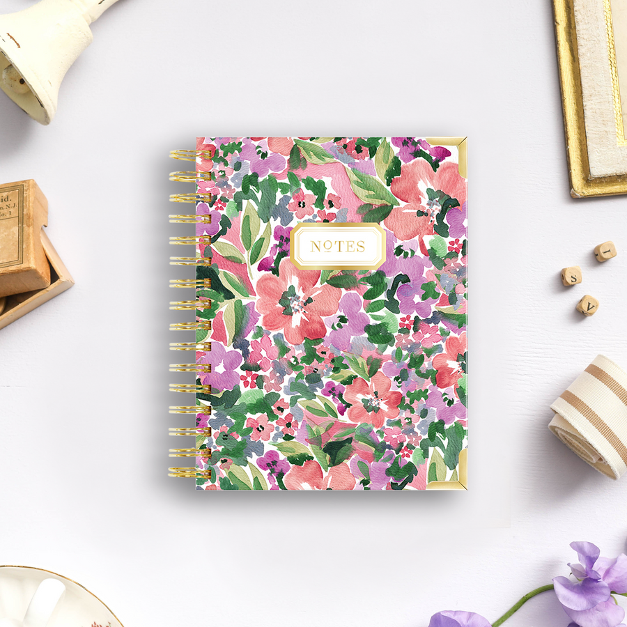 mini notebook with pink, red, and purple flowers, green leaves, lilac background, wood box, bell, fabric, flowers, dish, picture frame