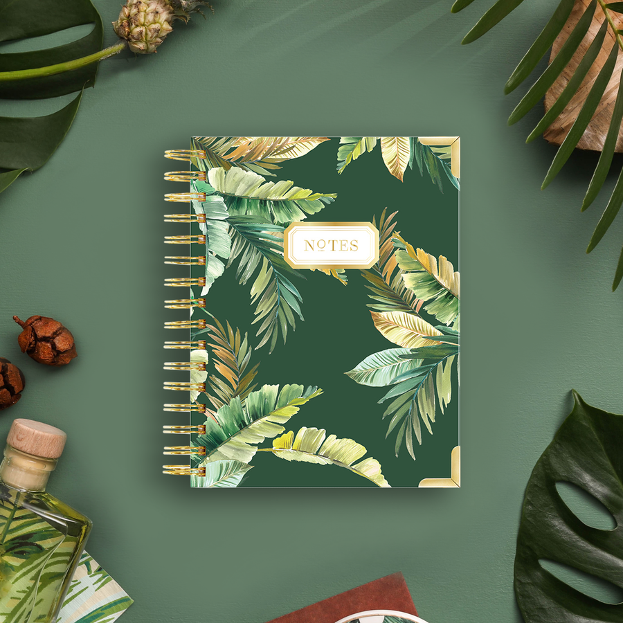 mini notebook with green and gold tropical leaves on dark green background, bottle, acorns, leaves