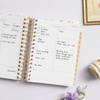 mini weekly planner, open book, written on pages, gold binding and tabs, lilac background, fabric, frame