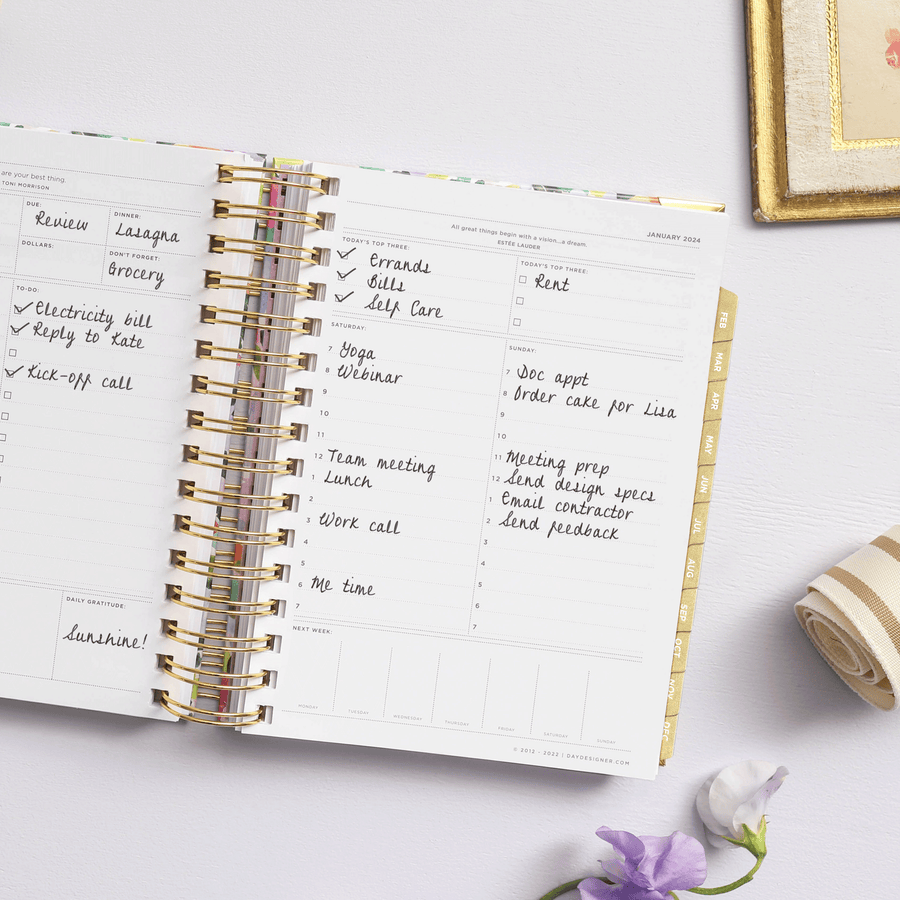 mini weekly planner, open book, written on pages, gold binding and tabs, lilac background, fabric, frame