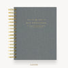 A gray linen-textured spiral notebook cover with gold wire binding and gold foil text reading 'DAY DESIGNER' on a white background.