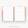 An open 12-month spiral-bound planner or calendar showing a monthly overview layout on white pages, with a pink cover edge and gold wire binding, centered on a light gray background with the text '12-MONTH OVERVIEW' below.