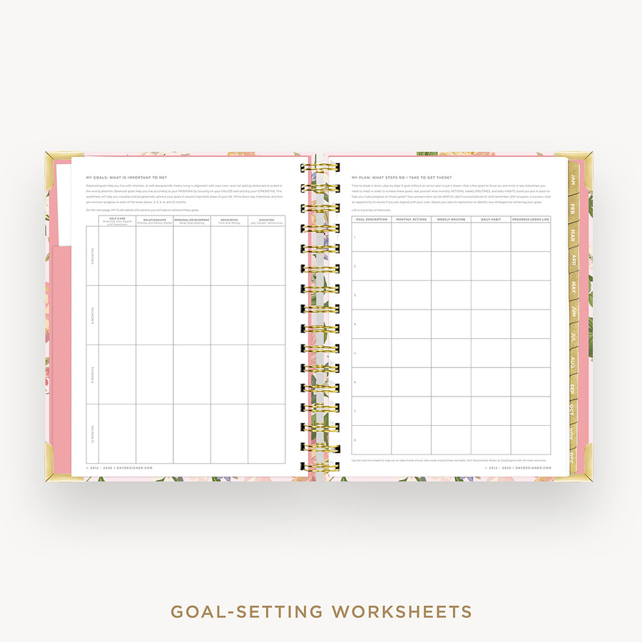 An open spiral-bound planner or notebook showing two printed goal-setting worksheet pages with pink floral border accents, photographed on a light gray background with the text 'GOAL-SETTING WORKSHEETS' below.