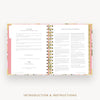 An open spiral-bound journal or planner showing printed introduction and instruction pages, with a pink and gold floral-patterned cover and the text 'INTRODUCTION & INSTRUCTIONS' below.