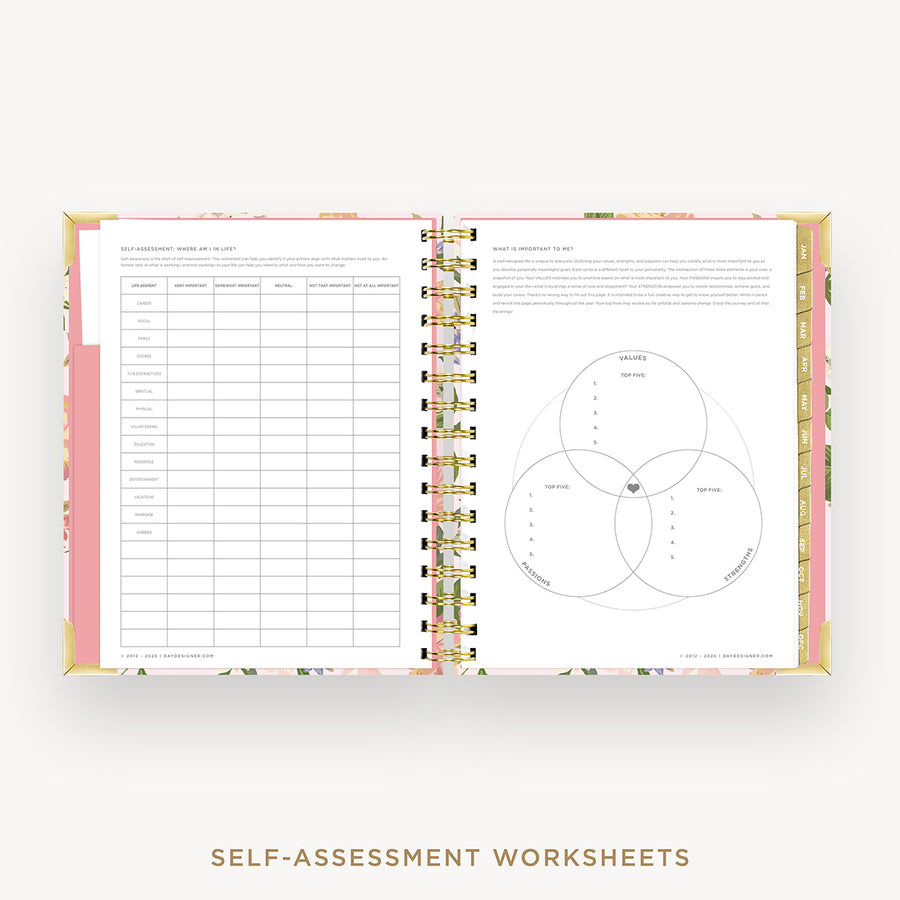 An open spiral-bound workbook showing two printed worksheet pages: a table on the left and a Venn diagram with text on the right. The cover and inner edges have a pink floral pattern, and the pages are held together by gold-tone spiral rings.