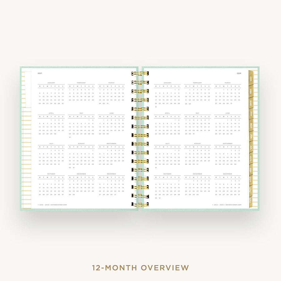 An open spiral-bound planner showing a 12-month calendar overview layout on white pages, with gold rings and a pale mint border, centered on a light gray background with the text '12-MONTH OVERVIEW' below.