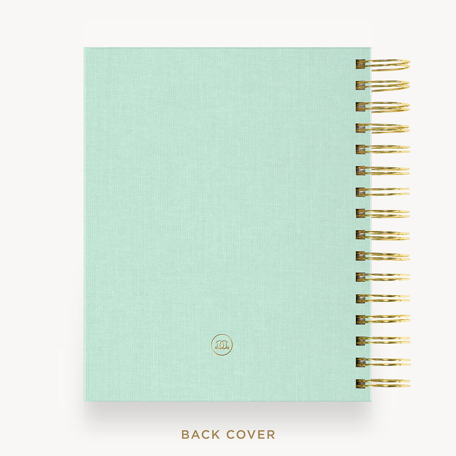 A mint green textured spiral notebook with gold wire binding and a small circular logo near the bottom, shown on a white background with the text 'BACK COVER' underneath.