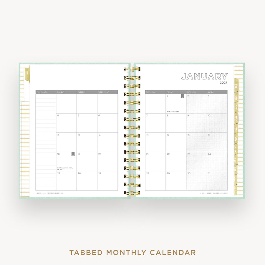 An open monthly calendar planner with two visible interior spreads showing January 2027, bound by gold-toned metal rings. The pages are white with light gray grid lines and a pale mint border.