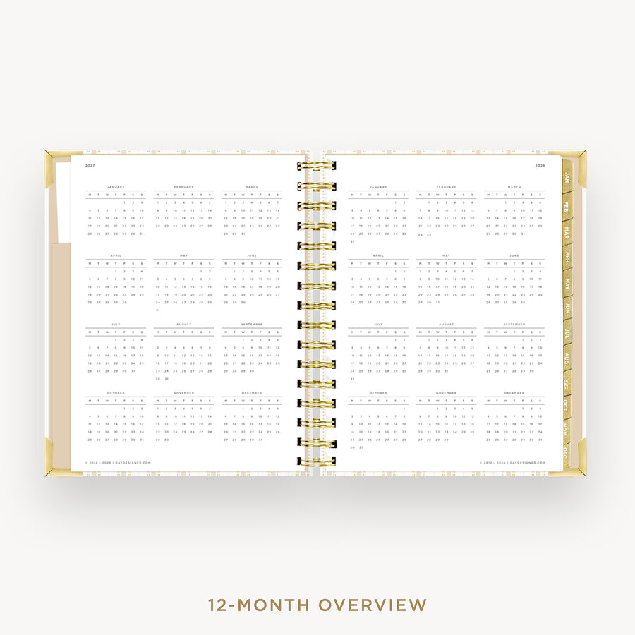 An open 12-month overview planner spread on a light gray background, showing a clean white interior with gold spiral binding and gold page edges. Text below reads '12-MONTH OVERVIEW'.