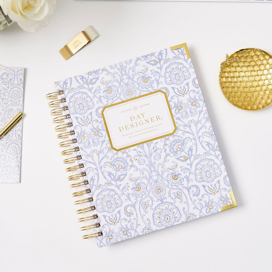 blue and gold block print planner cover, gold logo, binding, dish, pen loop clip, and pen, notebook, white rose