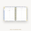 Open daily planner with spiral binding on a white background