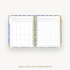Open wire-bound notebook displaying goal-setting worksheets on a white background.