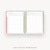 Open wire-bound notebook displaying goal-setting worksheets on a white background.